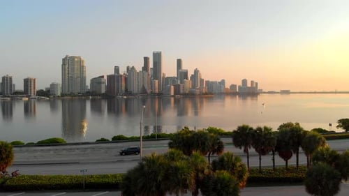 Rising drone shot over bikers and road and Miami skyline