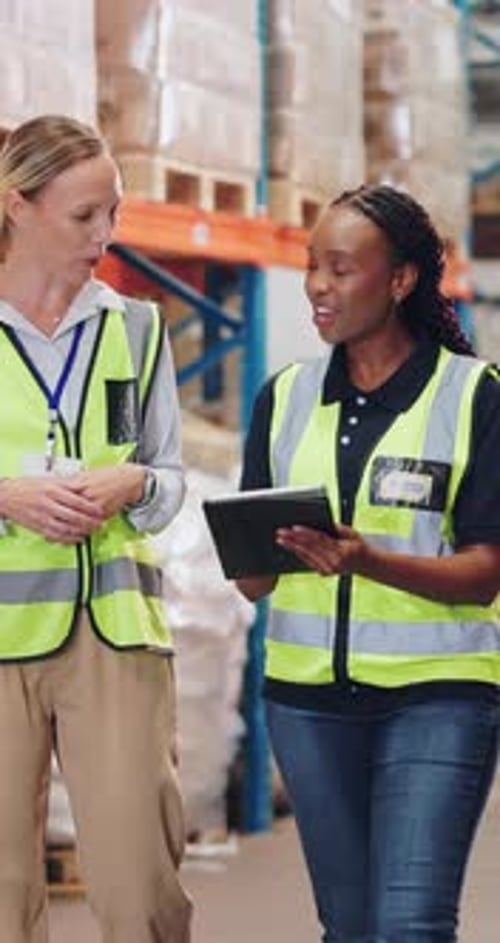 Discussion, logistics and people with tablet in warehouse with walking for checking stock inventory
