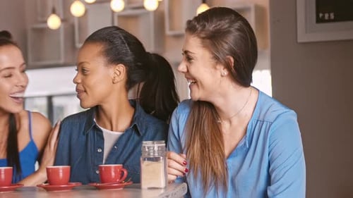 Three women talking and laughing together in cafe