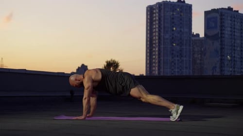 On the Roof Where a View of the City Opens the Athlete Performs Exercises
