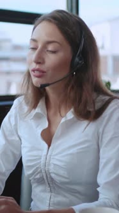 A Professional Woman Wearing a Headset Conducting Work in a Modern Office Setting Environment