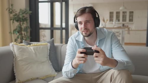 Young Man Playing Video Game on Couch at Home