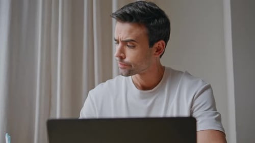 Concerned Man Looking Laptop Screen with Serious Expression in Office Closeup