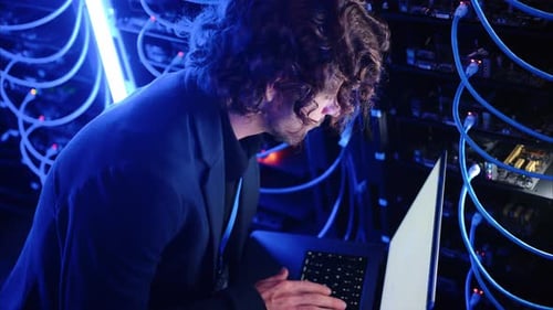 Man analysing servers and programming on a computer in a data center