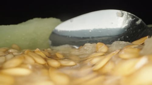 La caméra glisse à l'intérieur du melon sur les os, la cuillère en arrière-plan. Très gros plan