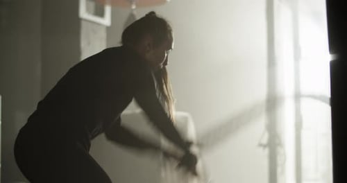 Strong Athletic Woman Training with Battle Rope in Gymnasium