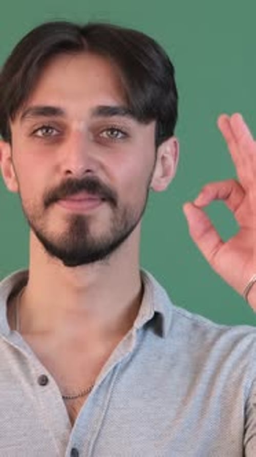 Young Man Making Ok Gesture on Green Background