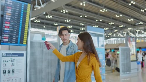 Asian passengers checking flight information on timetable in airport.