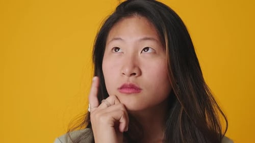 Close up, young woman thinking and making decision isolated over yellow background in studio
