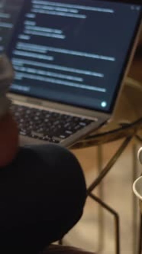 Une personne est profondément concentrée sur le codage sur son ordinateur portable avec une tasse de café chaud à côté d'elle
