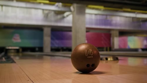 Bowling Ball Put on Alley with Blurred Lanes and Pins in Background
