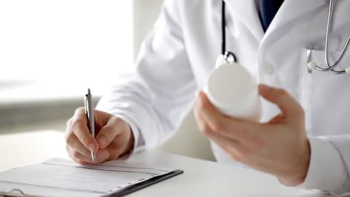 Male doctor writes prescription for patient close up in hospital setting