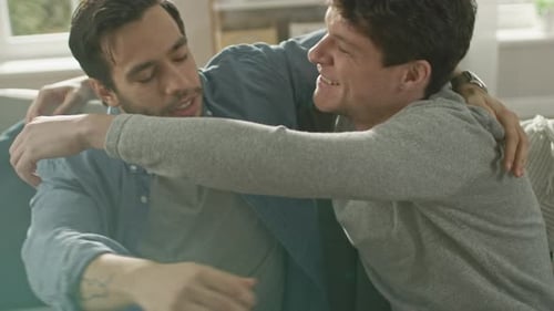 Loving Adult Men Embrace Affectionately on a Sofa