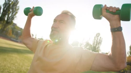 Senior Man Lifting Weights Outdoors in Sunlight