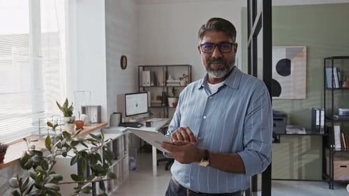 Portrait of Mature Indian Businessman Posing at Modern Office with Tablet