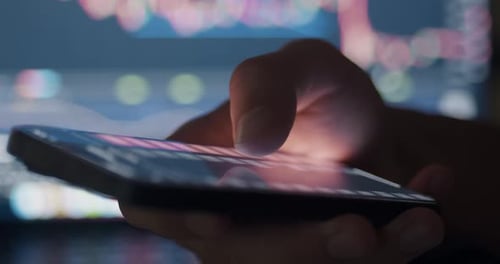 Hand Using Phone With Data And Graphs Close Up