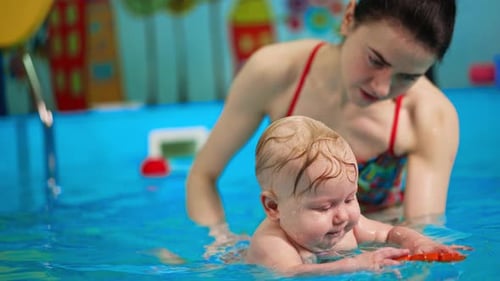 Small infant tries to reach the toy in the swimming pool.
