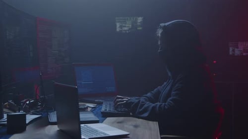 Un mystérieux hacker travaille assidûment tard dans la nuit dans une pièce sombre