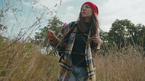Young Woman Hiking Through a Grassy Field