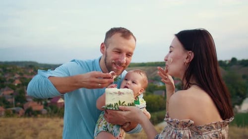 Happy Family with Baby Celebrate First Year Eat Cake in Field at Sunset Autumn and Lifestyle