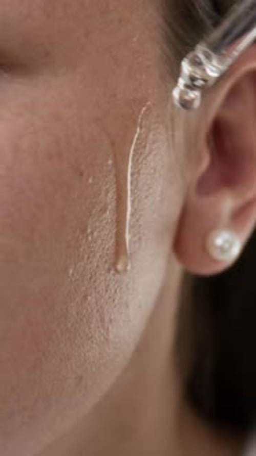 Woman Applies Facial Serum with Glass Dropper