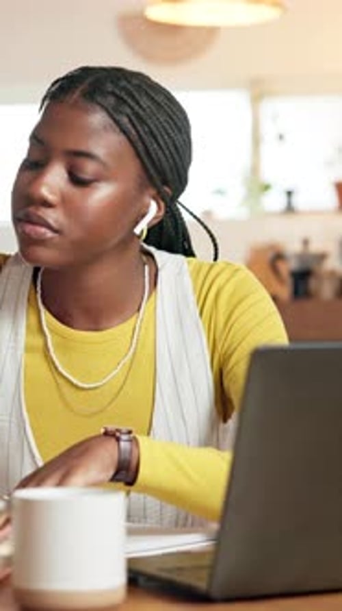 Woman working on laptop, writing in a notebook