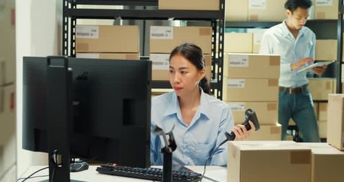 Asian girl and man use barcode machine scan record customer online data in cardboard box.