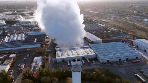 Industrial Factory with Smokestack Emitting White Smoke