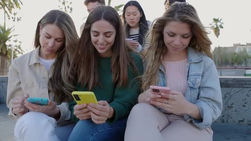 Young Adults Using Mobile Phones Together Outdoors