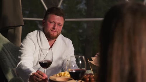Un homme soulève un verre à vin en clignotant avec une femme
