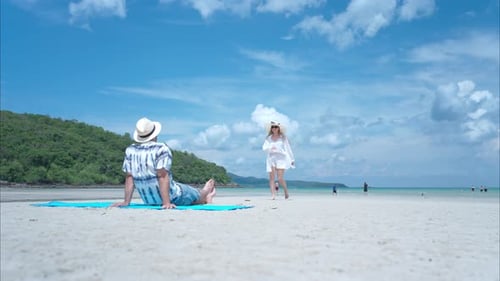Young couple on vacation on a white sandy beach, clear sky and sea