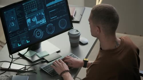 Junger männlicher Programmierer arbeitet am PC am Schreibtisch im Nachtbüro