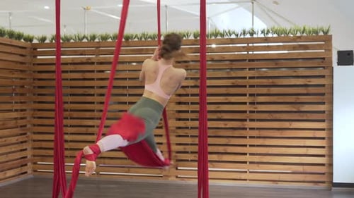 Beautiful fit girl dressed in tight leggins and pink top practising fly yoga/fitness. The sportsgirl
