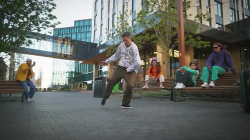 Young And Stylish Male Hip Hop Dancer Is Freestyling On City Street Among Modern Buildings In the