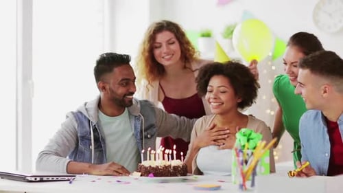 Happy multiethnic office team celebrates birthday with cake and a wish indoors