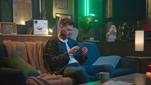 Man on Couch Using Tablet Device at Night