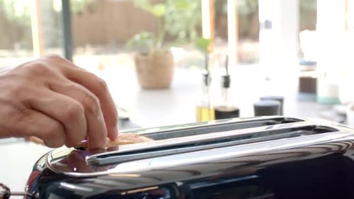 Placing Bread Slices into Toaster in Kitchen