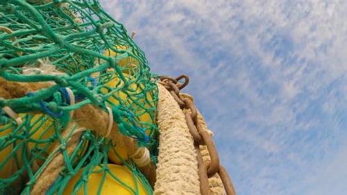 Tilt down shot of fishing net with chains and buoys. Close up, upward view
