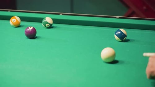 CloseUp of Cue Stick Striking White Billiard Ball on Green Pool Table