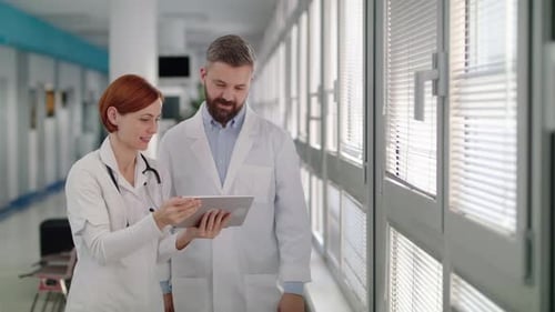A Portrait of Man and Woman Doctor with Tablet Standing in Hospital