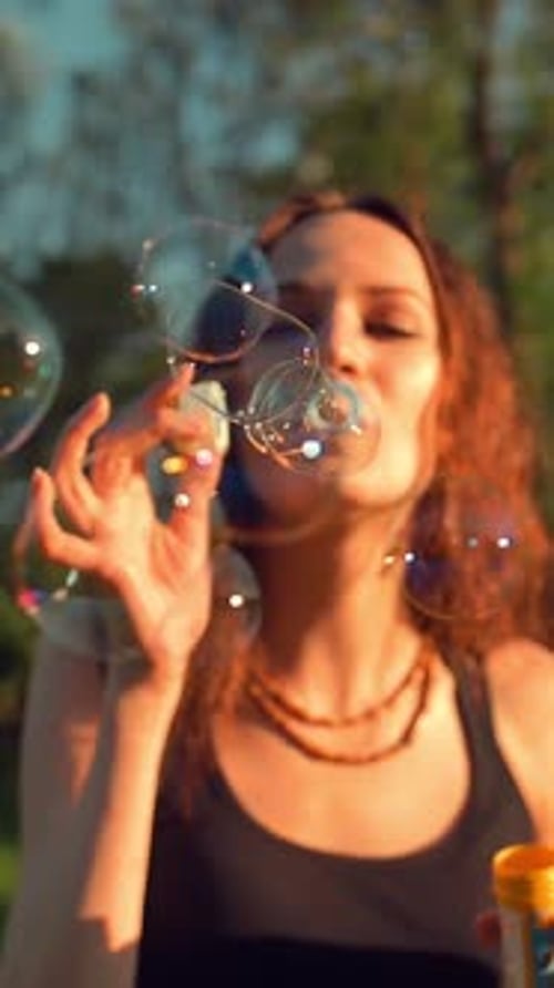 Vertical of Front View of Young Pretty Adult Girl Making Soap Bubbles Beautiful Tree with Orange