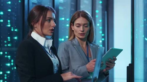 Dos mujeres analizan datos en una sala de servidores de alta tecnología para demostrar su colaboración