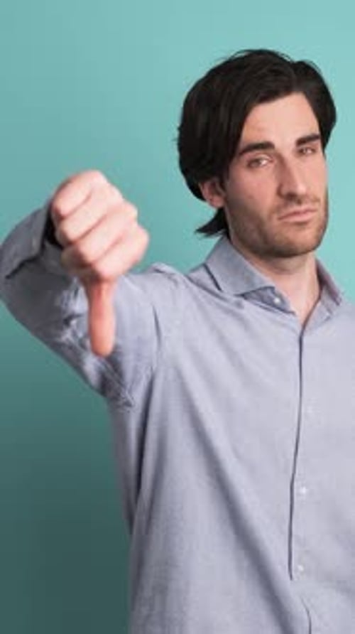 Upset Man Showing Thumb Down in Blue Studio