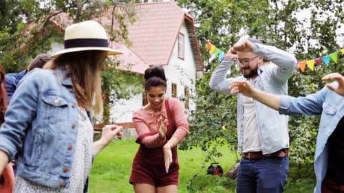 Happy friends dancing together at summer garden party in slow motion