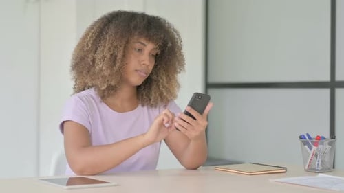 Woman using smartphone while seated at table