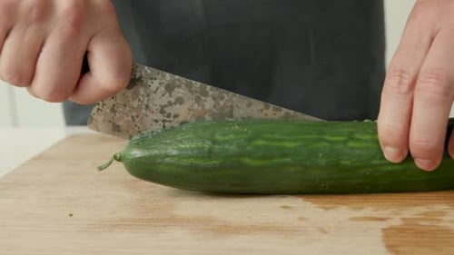 Slicing a Cucumber on Wooden Cutting Board