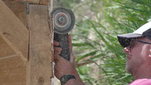 Man Cutting Wood with Power Tool Outdoors