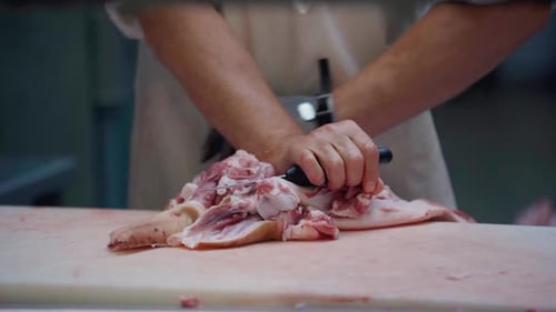 Butcher Carving Fresh Cuts of Raw Pork
