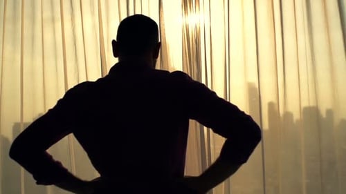 Man Silhouette Looks Out Apartment Window at Sunrise