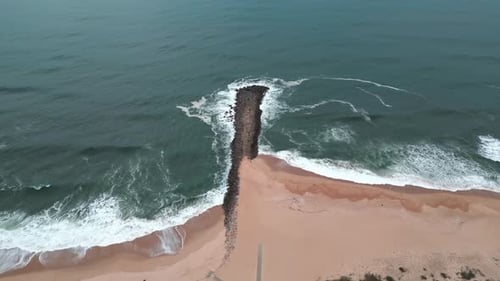 Aerial view of the ocean reaching the shore in a moody day with nice waves and colors.